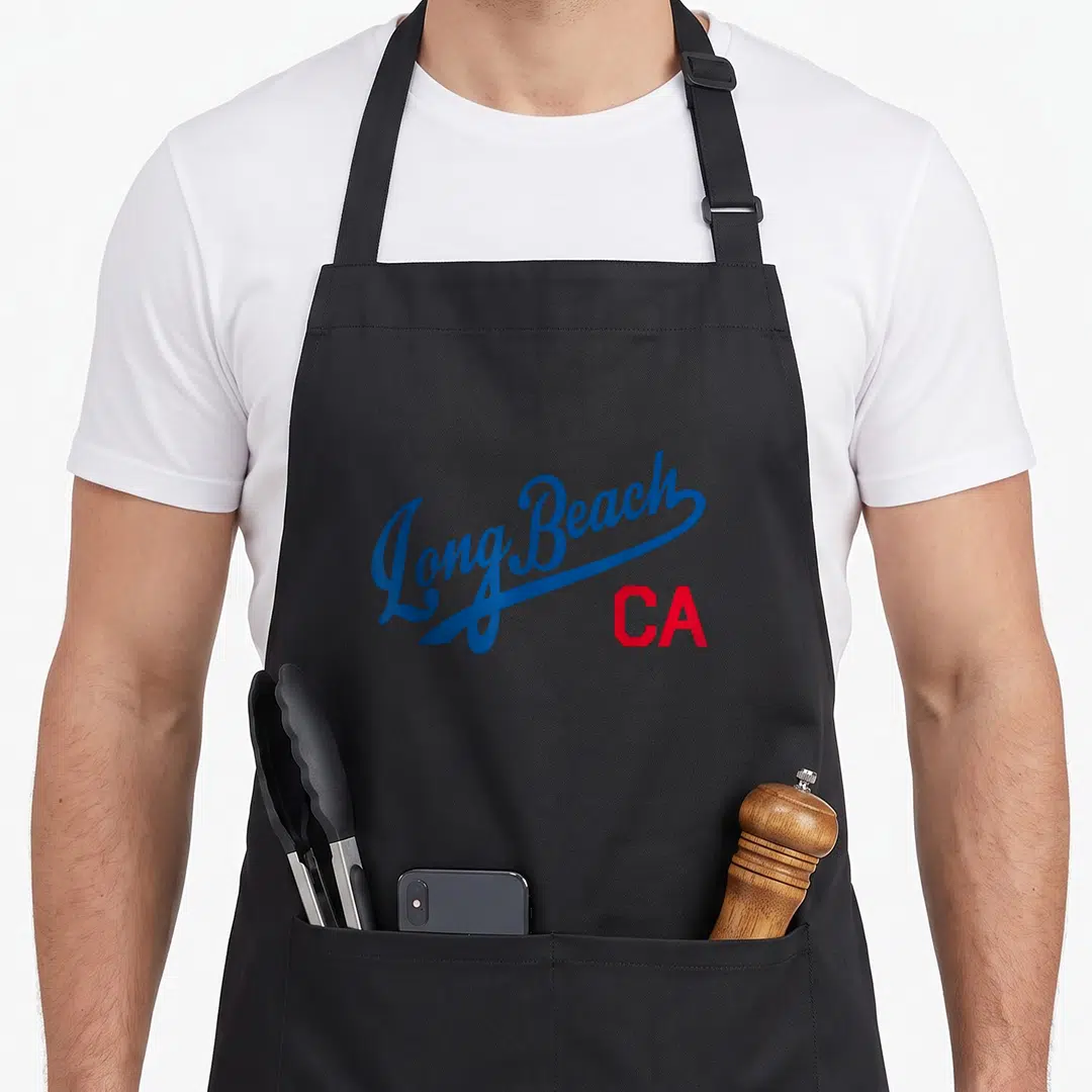 Beach king apron - Long Beach script text in blue with red CA abbreviation below — shown on a black cotton canvas apron against a white background