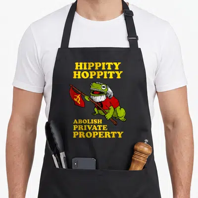 Hoppity meme apron - Green bearded frog holding red flag with yellow Hippity Hoppity Abolish Private Property text — shown on a black cotton canvas apron against a white background