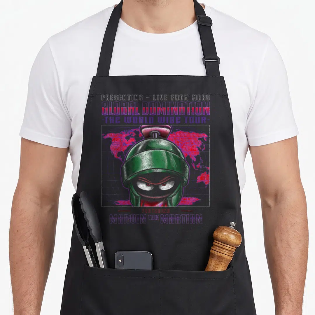Marvin looney tune apron - Green robot head over red world map and purple grid with presenting live from mars text — shown on a black cotton canvas apron against a white background