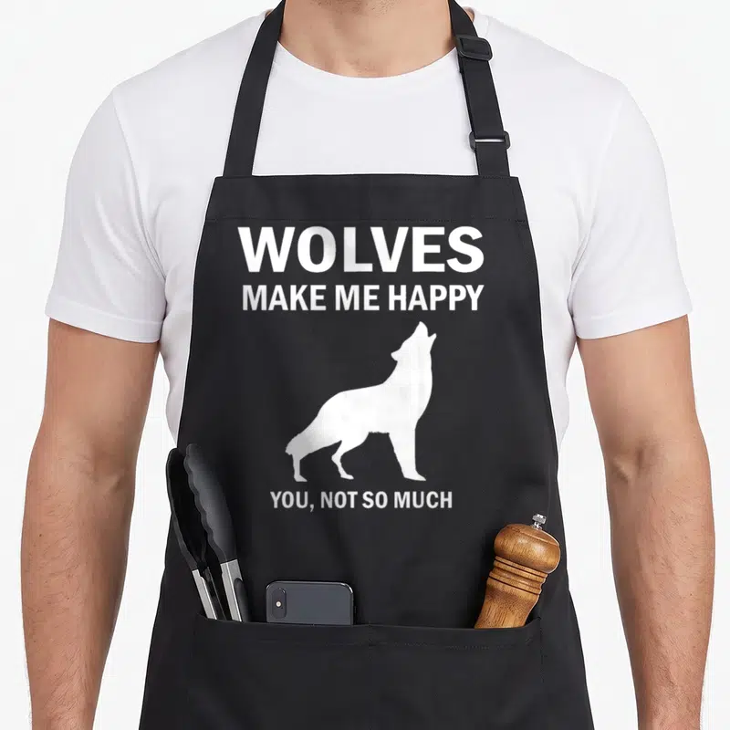 Animal wolves apron - White wolf silhouette between text WOLVES MAKE ME HAPPY YOU NOT SO MUCH — shown on a black cotton canvas apron against a white background