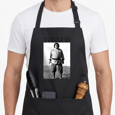 Anybody princess apron - ANYBODY WANT A PEANUT? text above a black and white photo of a man standing in a field — shown on a black cotton canvas apron against a white background