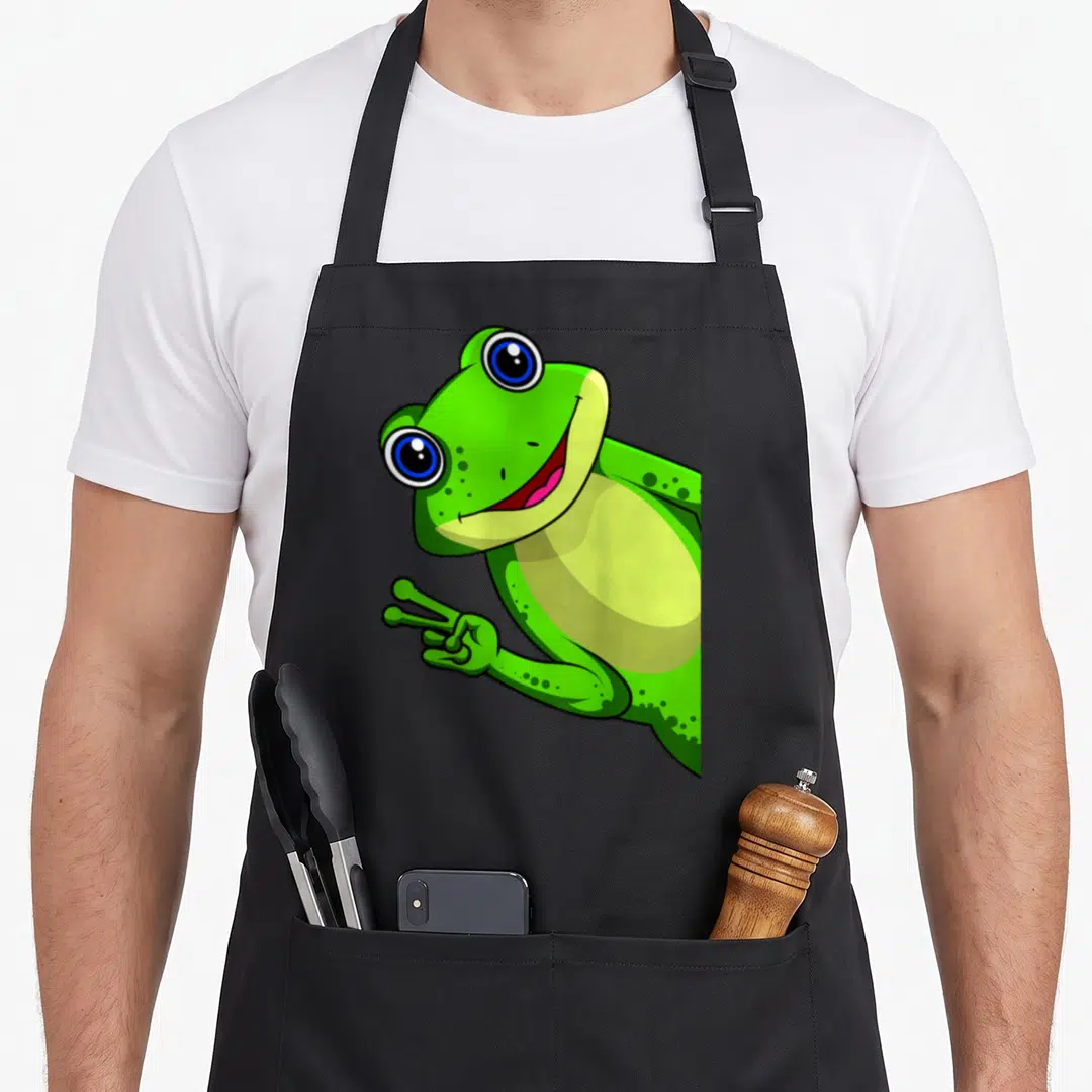 Cool animal frog aprons - Cartoon green frog with blue eyes holding up a peace sign hand gesture — shown on a black cotton canvas apron against a white background