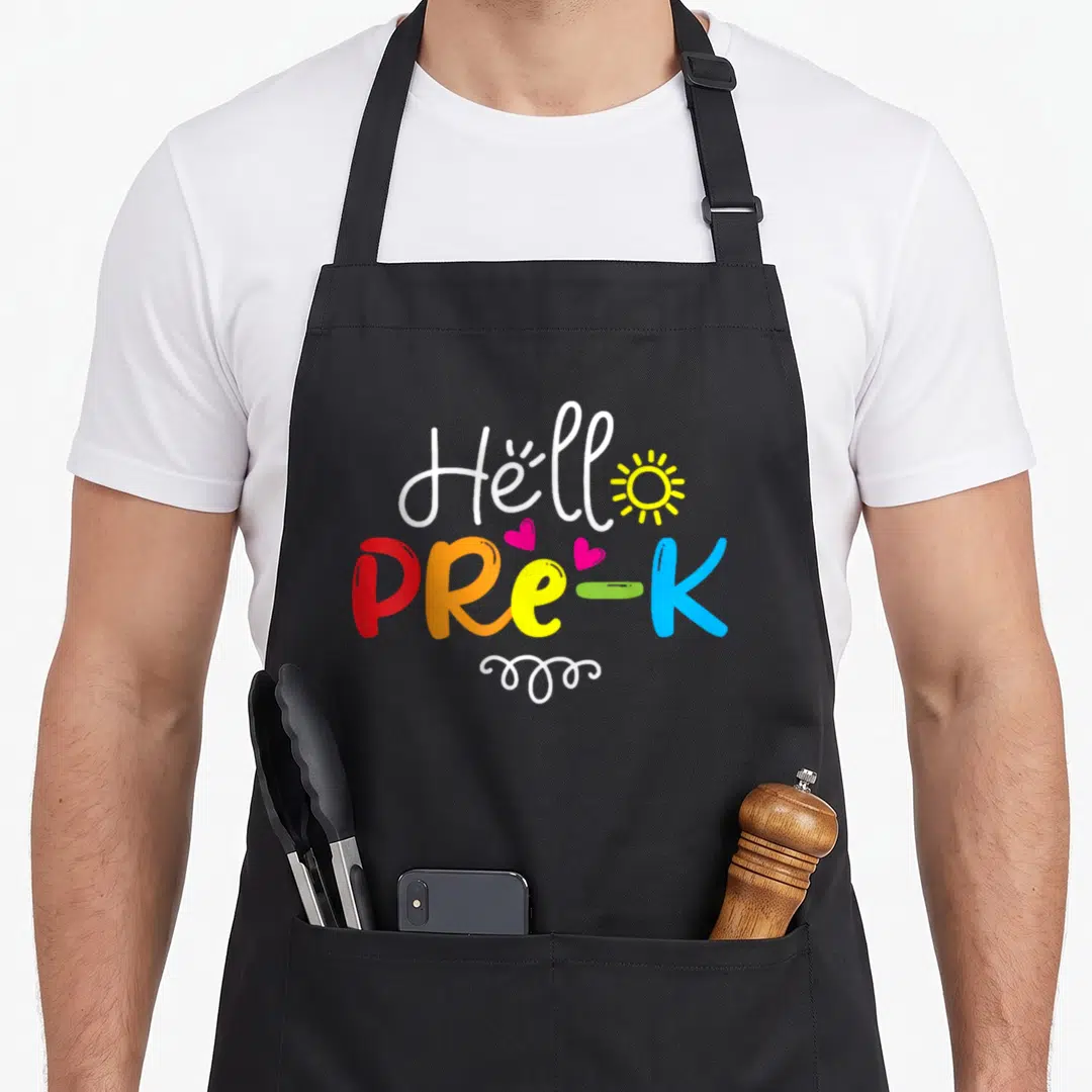 Hello pre teacher apron - Hello PRE-K text with sun hearts swirl in white red orange yellow blue pink — shown on a black cotton canvas apron against a white background