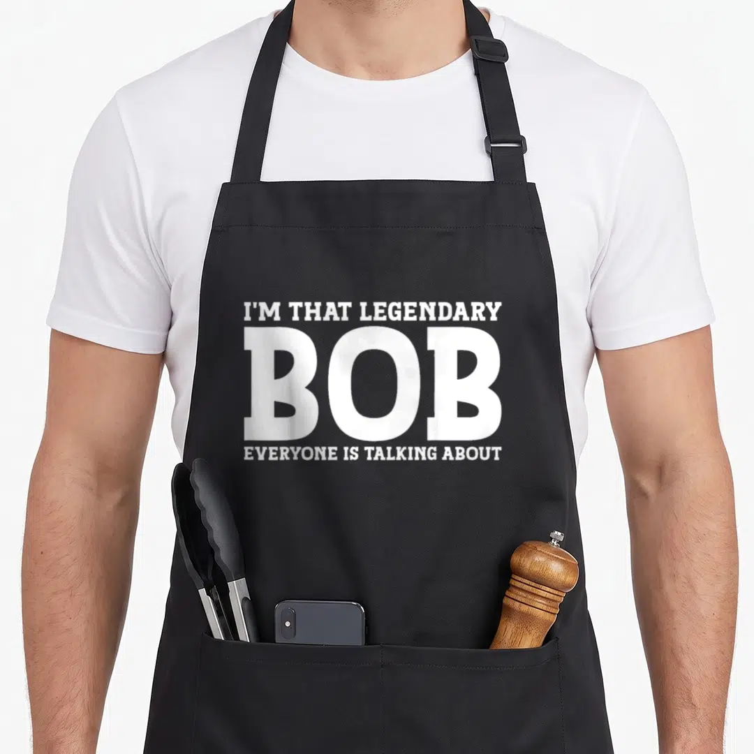 Funny bob personal apron - White stacked text I'M THAT LEGENDARY BOB EVERYONE IS TALKING ABOUT — shown on a black cotton canvas apron against a white background