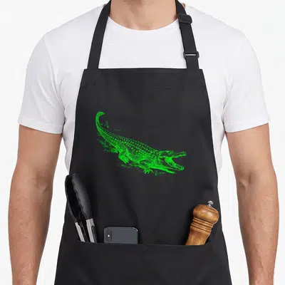 Illustrative alligator gar apron - Green line-art drawing of a crocodile with an open mouth — shown on a black cotton canvas apron against a white background