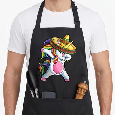 Unicorn mexican apron - Cartoon white unicorn dabbing while wearing a colorful sombrero with rainbow mane — shown on a black cotton canvas apron against a white background