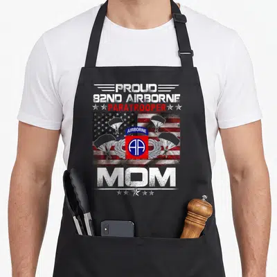 82nd mother's apron - 82nd Airborne insignia over distressed US flag with three parachutes and PROUD 82ND AIRBORNE — shown on a black cotton canvas apron against a white background