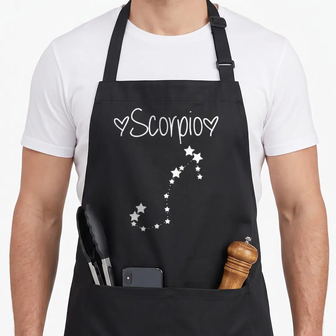 Star october birthday apron - White Scorpio text with two hearts and star constellation pattern — shown on a black cotton canvas apron against a white background