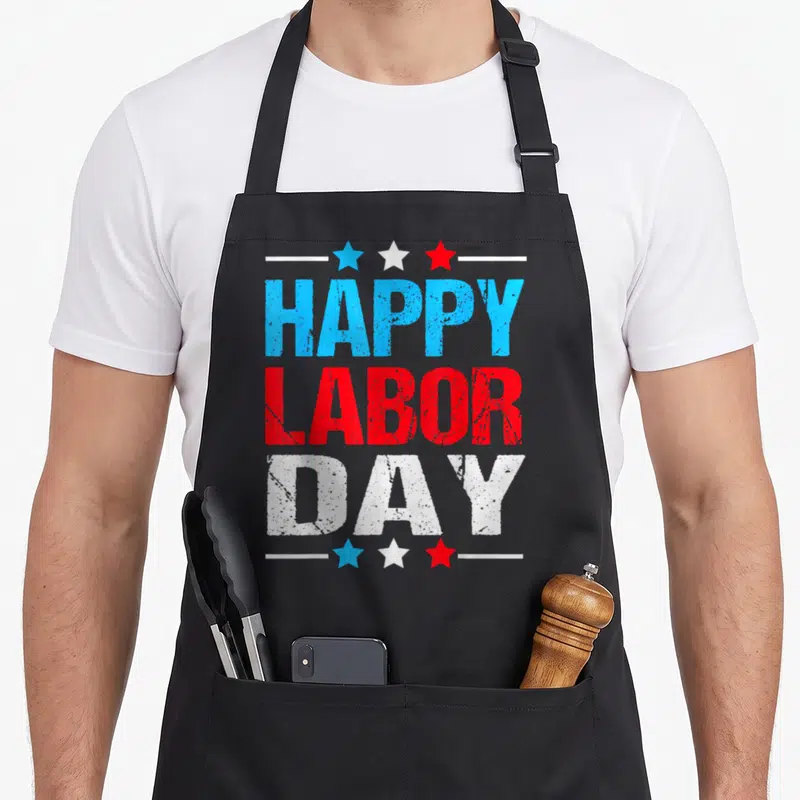 Labor patriots apron - Stacked distressed HAPPY LABOR DAY text in blue red white with three stars and lines — shown on a black cotton canvas apron against a white background