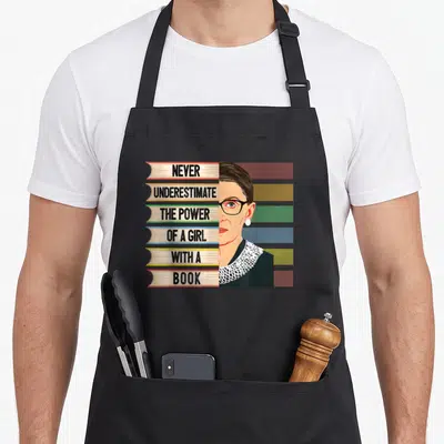 Feminist book apron - Stack of six books with quote and Ruth Bader Ginsburg portrait in minimalist style — shown on a black cotton canvas apron against a white background