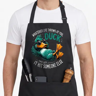 Duck sarcastic apron - Teal cartoon duck wearing black sunglasses with white text arching above and below — shown on a black cotton canvas apron against a white background