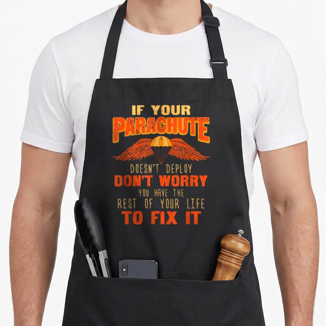 Skydiver skydiving apron - Orange parachute with wings and sarcastic text about deployment failure — shown on a black cotton canvas apron against a white background