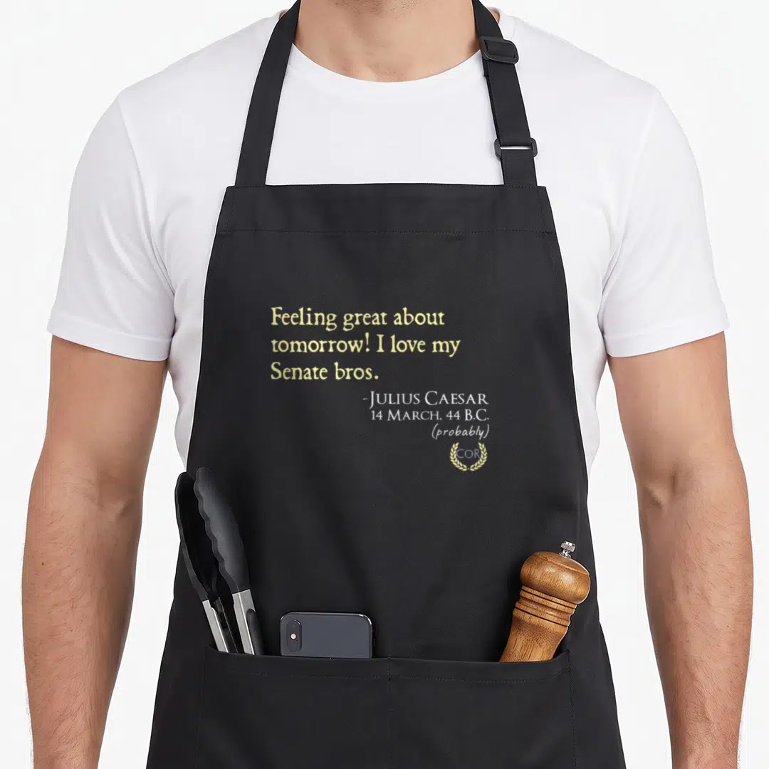 Julius caesar apron - Beige and yellow text quote by Julius Caesar with a small laurel wreath at the bottom right — shown on a black cotton canvas apron against a white background