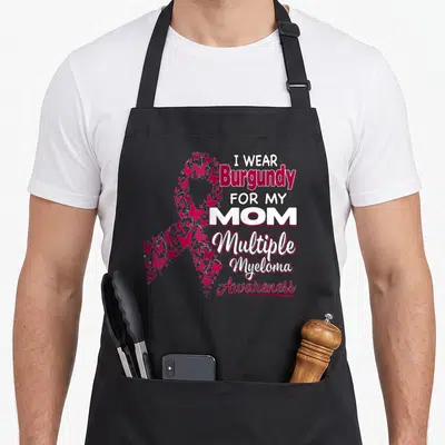 Multiple ribbon mom apron - I WEAR BURGUNDY FOR MY MOM text beside a ribbon made of burgundy butterflies — shown on a black cotton canvas apron against a white background