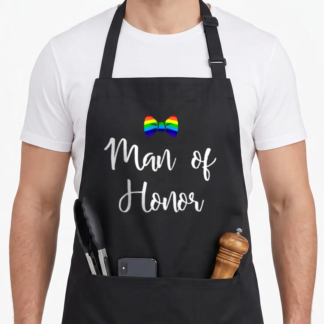 Bachelor gay pride apron - Rainbow bow tie above white Man of Honor script text — shown on a black cotton canvas apron against a white background