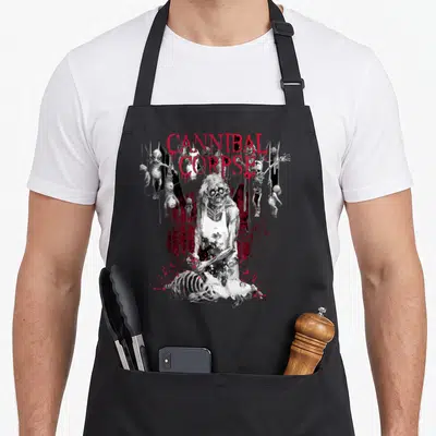 Butcher cannibal corpse apron - Red CANNIBAL CORPSE text above grey zombie standing over skeleton with hanging bodies — shown on a black cotton canvas apron against a white background