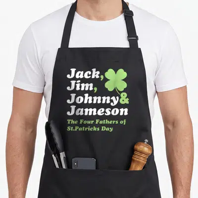 Saint father day apron - Jack Jim Johnny Jameson Four Fathers text with green shamrock — shown on a black cotton canvas apron against a white background