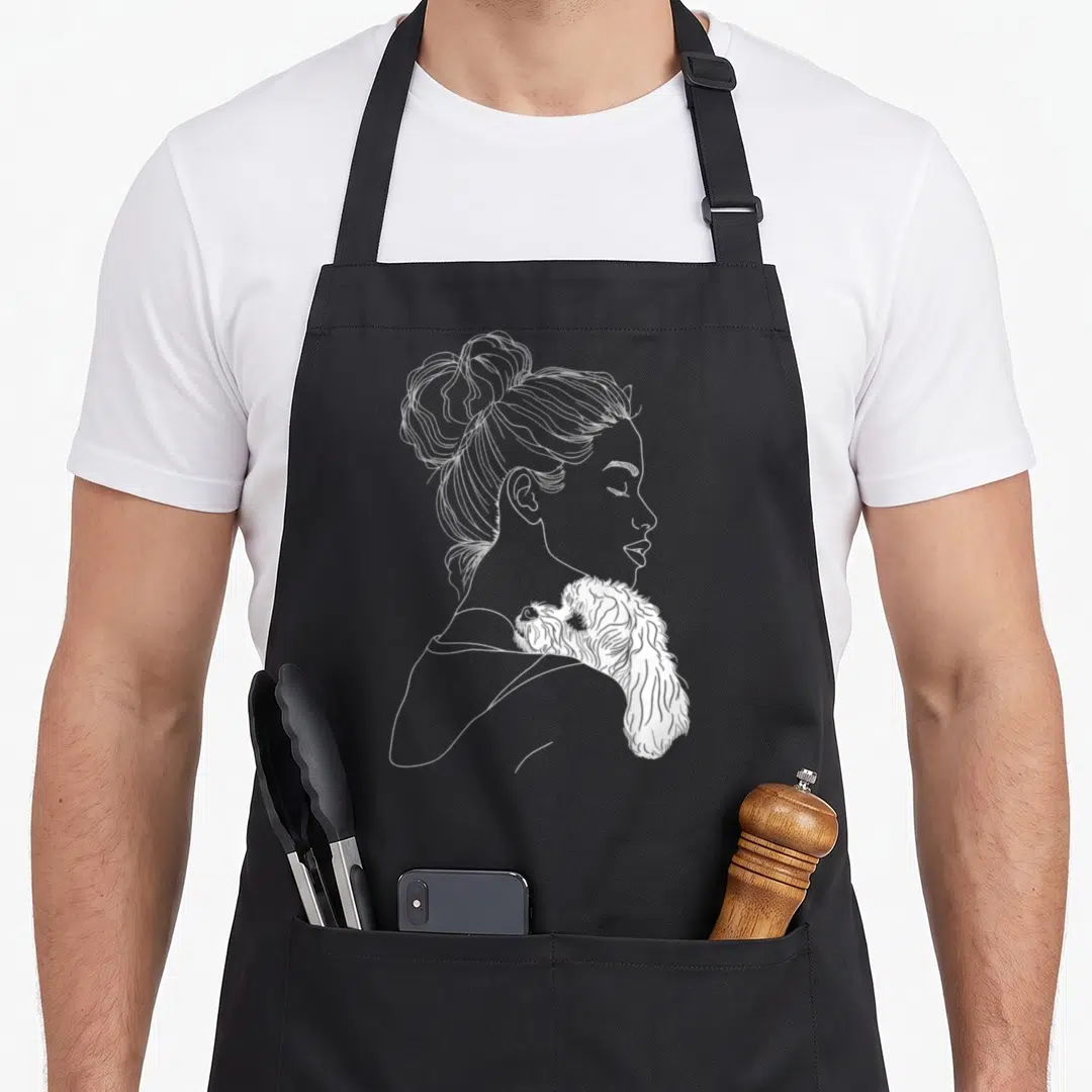 Frise mother's day aprons - White line art of woman profile with fluffy dog on shoulder — shown on a black cotton canvas apron against a white background