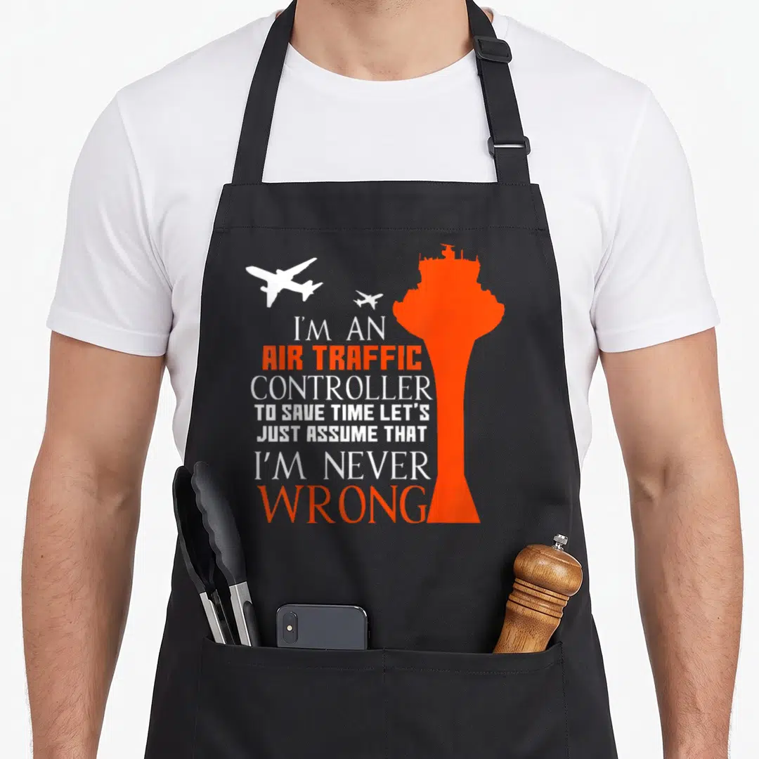 Wrong air traffic controller apron - Orange tower and two white planes with sarcastic text about never being wrong — shown on a black cotton canvas apron against a white background