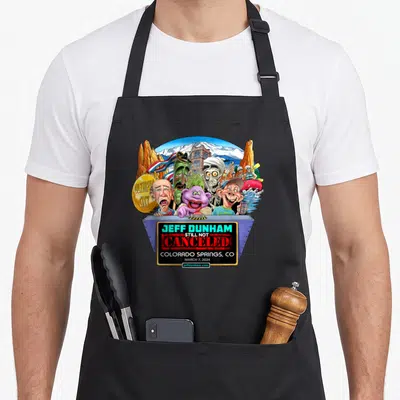 Jeff spring apron - Jeff Dunham Still Not Canceled caricatures mountain background blue box text — shown on a black cotton canvas apron against a white background