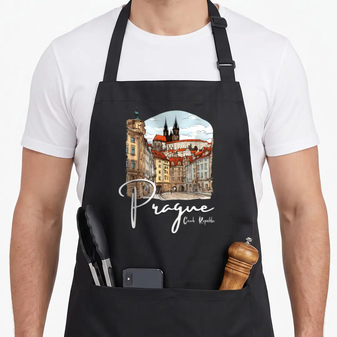 Prague czech apron - Watercolor Prague cityscape with church towers and white script text on black fabric — shown on a black cotton canvas apron against a white background