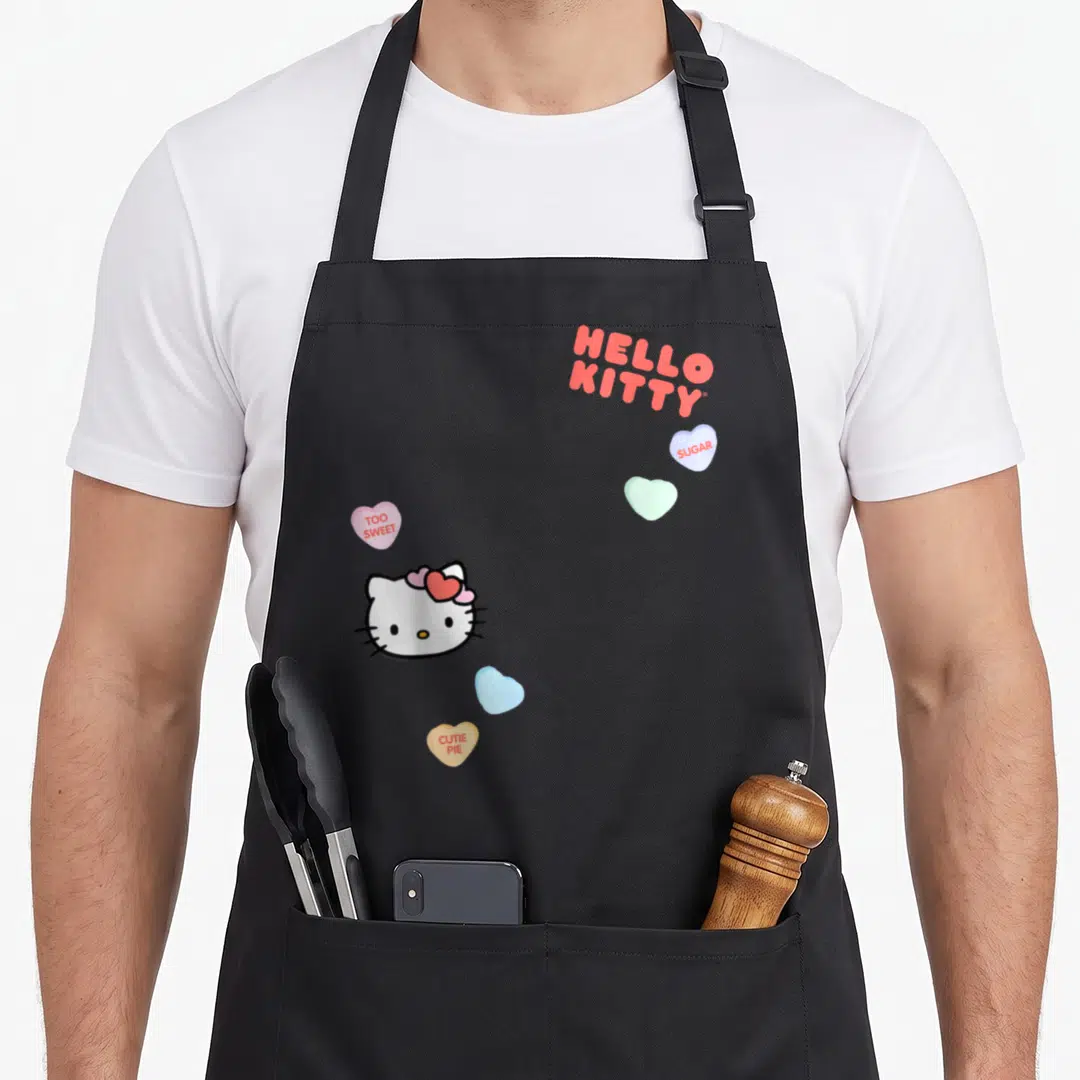 Retro valentine cotton candy apron - Hello Kitty head with red bow and four candy hearts reading Sugar, Too Sweet — shown on a black cotton canvas apron against a white background