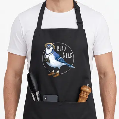 Nerd blue bird apron - Cartoon blue jay with binoculars and glasses beside stacked BIRD NERD text inside a white circle — shown on a black cotton canvas apron against a white background