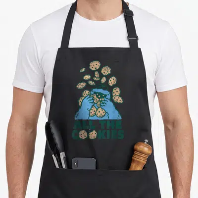 Cookie cookies apron - Blue character holding tan cookies with All The Cookies text below — shown on a black cotton canvas apron against a white background