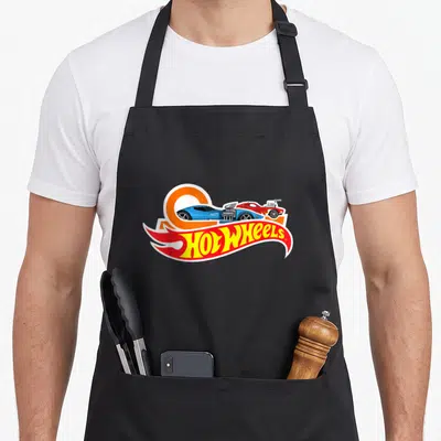 Car wheel apron - Hot Wheels logo with blue and red toy cars over orange circle — shown on a black cotton canvas apron against a white background