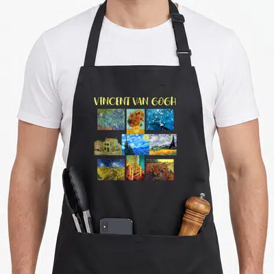 Masterpiece van gogh apron - Nine Van Gogh paintings in a grid under yellow VINCENT VAN GOGH text on black fabric — shown on a black cotton canvas apron against a white background