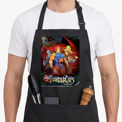 Funny poster shot apron - Lion-O central ThunderCats Classic cartoon group with red blue orange yellow villain — shown on a black cotton canvas apron against a white background