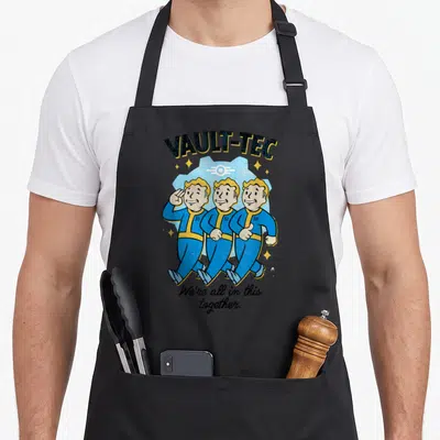 Funny together novelty apron - Three Vault Boys walking in blue suits under Vault-Teck logo with slogan — shown on a black cotton canvas apron against a white background
