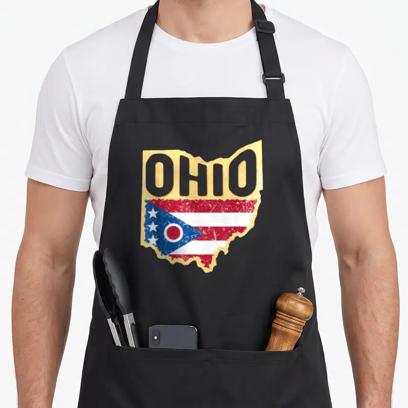 State akron apron - Ohio state map shape with distressed flag and grey OHIO text on tan background — shown on a black cotton canvas apron against a white background