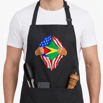 Guyanese blood apron - Two hands tearing USA flag revealing Guyana flag in cartoon style — shown on a black cotton canvas apron against a white background