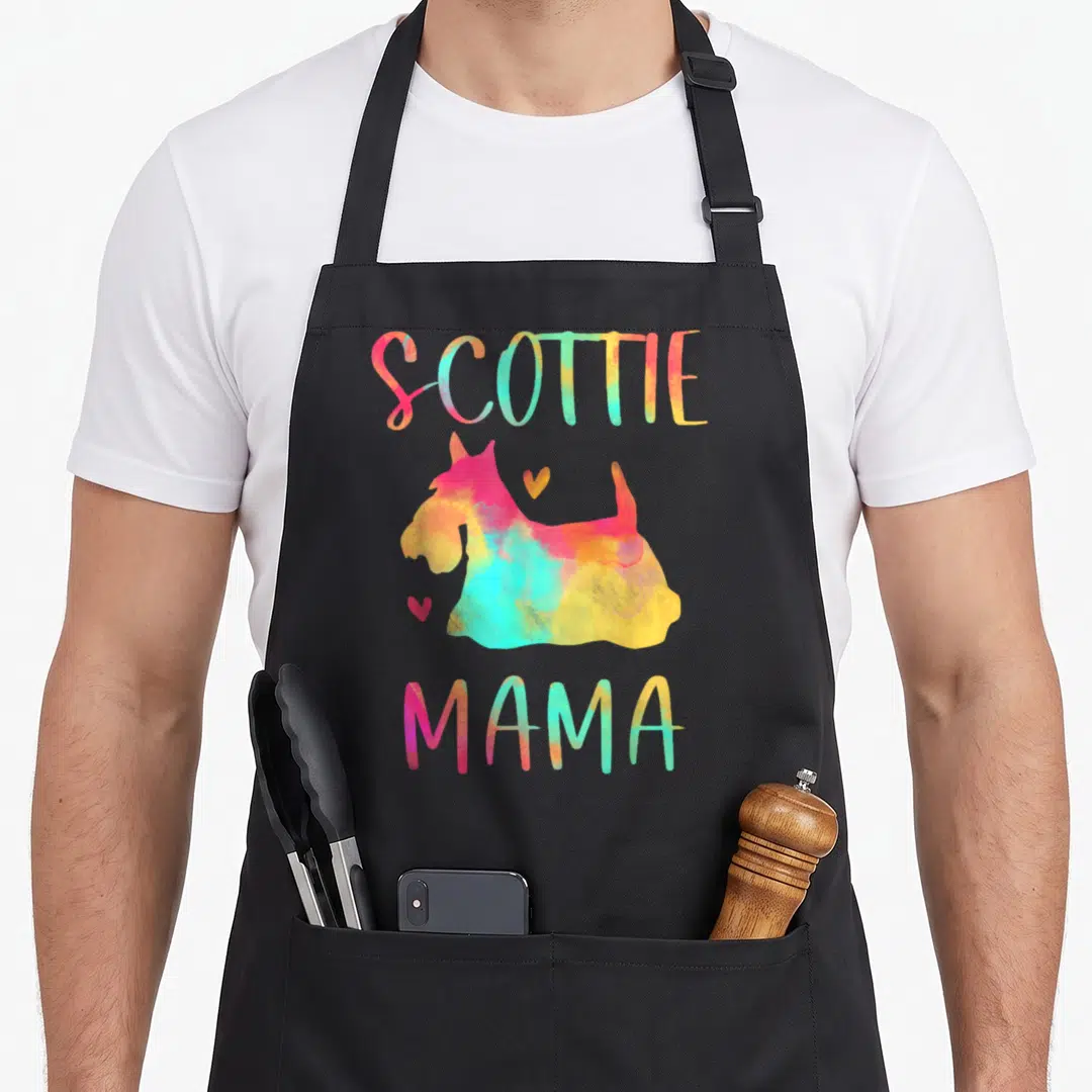 Scottie mama dog apron - Watercolor Scottish Terrier silhouette with SCOTTIE MAMA text and two hearts in pink yellow — shown on a black cotton canvas apron against a white background