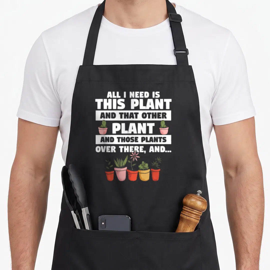 Plantsman plant apron - Stacked text quote flanked by two cacti above a row of five potted plants in red and pink pots — shown on a black cotton canvas apron against a white background