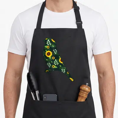Goldfinch the floral apron - Bird silhouette filled with yellow sunflowers and green leaves in cartoon style — shown on a black cotton canvas apron against a white background