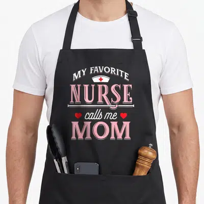 Mother white nurse apron - Stacked text My Favorite Nurse Calls Me Mom with pink hat and red hearts — shown on a black cotton canvas apron against a white background