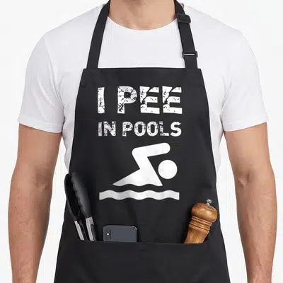 Pool summer aprons - I PEE IN POOLS text and white minimalist swimmer icon — shown on a black cotton canvas apron against a white background