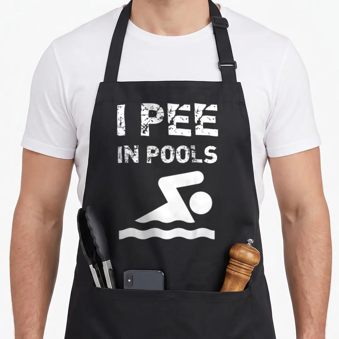 Pool summer aprons - I PEE IN POOLS text and white minimalist swimmer icon — shown on a black cotton canvas apron against a white background