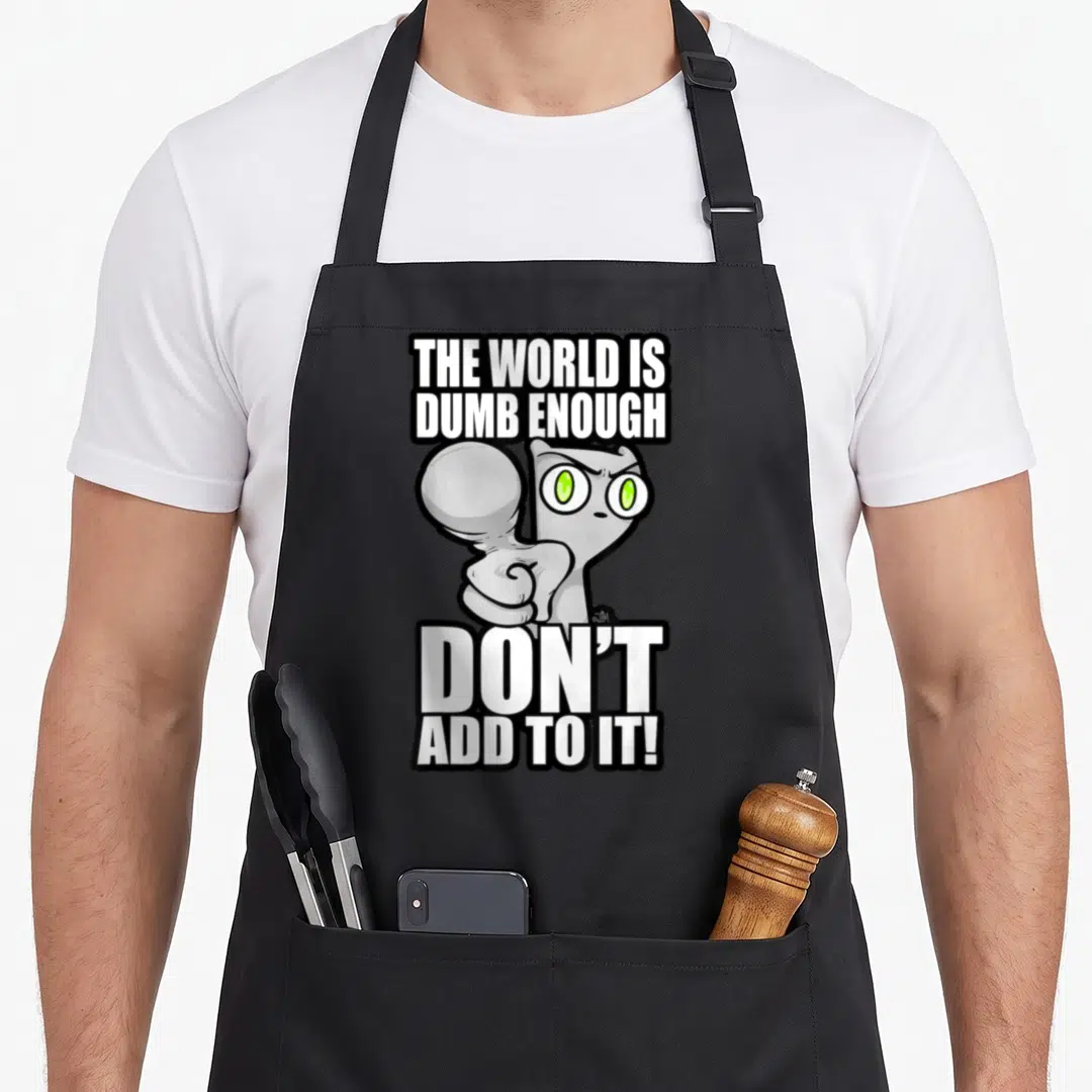Ill cartoon apron - Grey cartoon cat pointing forward between white text blocks saying the world is dumb enough — shown on a black cotton canvas apron against a white background