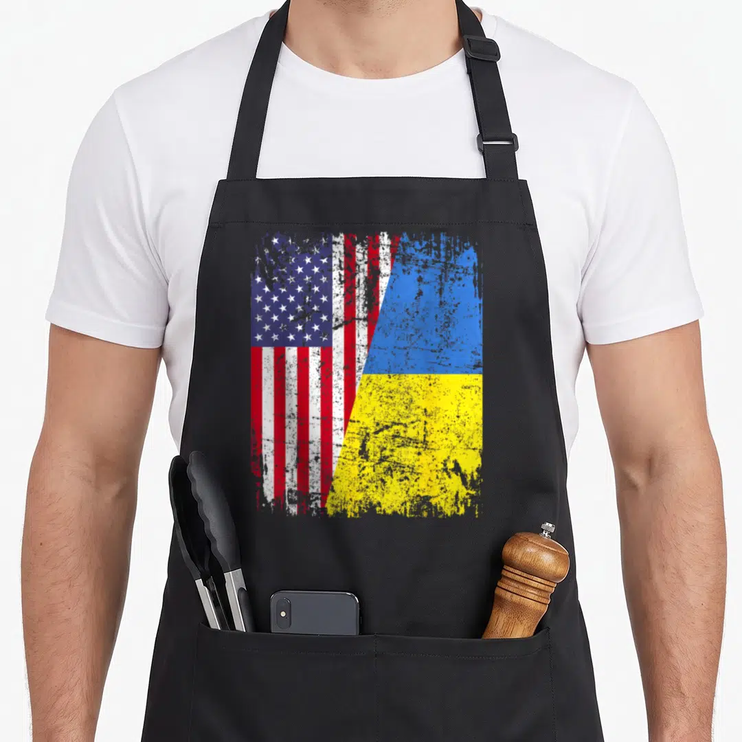 Ukrainian root american flag apron - Merged US and Ukraine flags in distressed red white blue and yellow — shown on a black cotton canvas apron against a white background