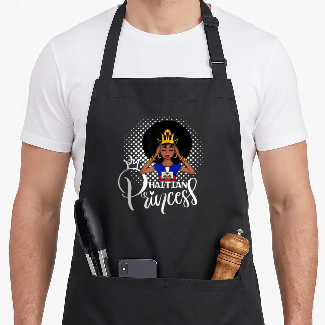 Funny haitian princess apron - Cartoon woman with gold crown and Haitian flag shirt, white halftone circle, 'HAITIAN — shown on a black cotton canvas apron against a white background