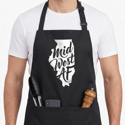 Midwest pride apron - White Illinois map silhouette with distressed grey Mid West AF lettering — shown on a black cotton canvas apron against a white background