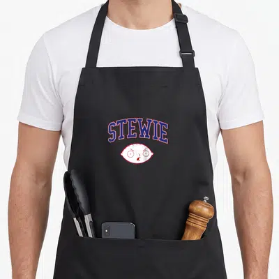 Lettering cartoon apron - Arched STEWIE text in blue and red above a cartoon baby head outline — shown on a black cotton canvas apron against a white background