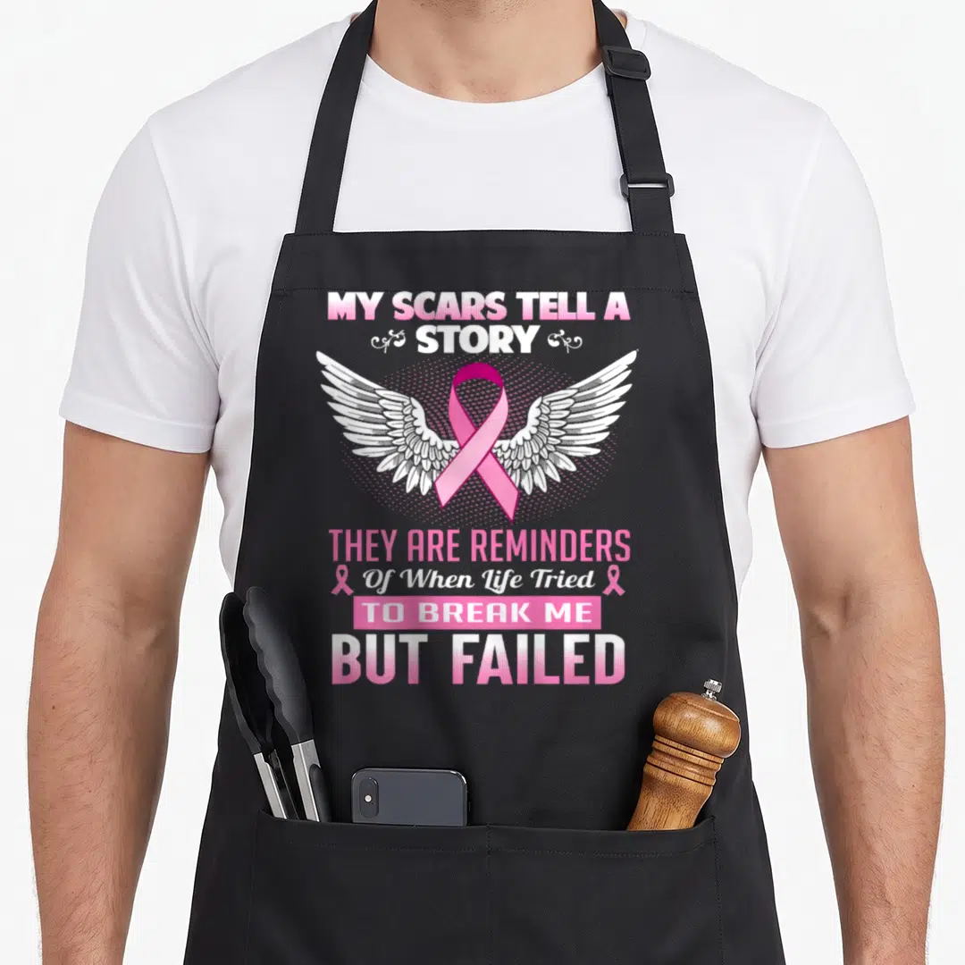 Scar breast cancer awareness aprons - Pink ribbon over white wings with My Scars Tell A Story text — shown on a black cotton canvas apron against a white background