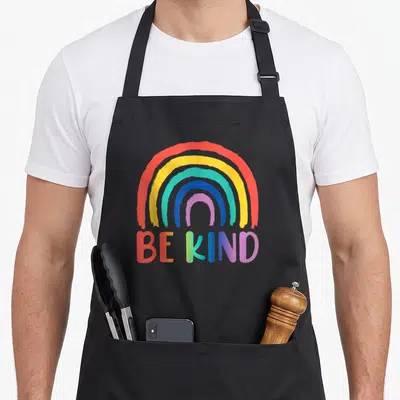 Choose rainbow apron - Rainbow arch and BE KIND gradient text on grey background — shown on a black cotton canvas apron against a white background