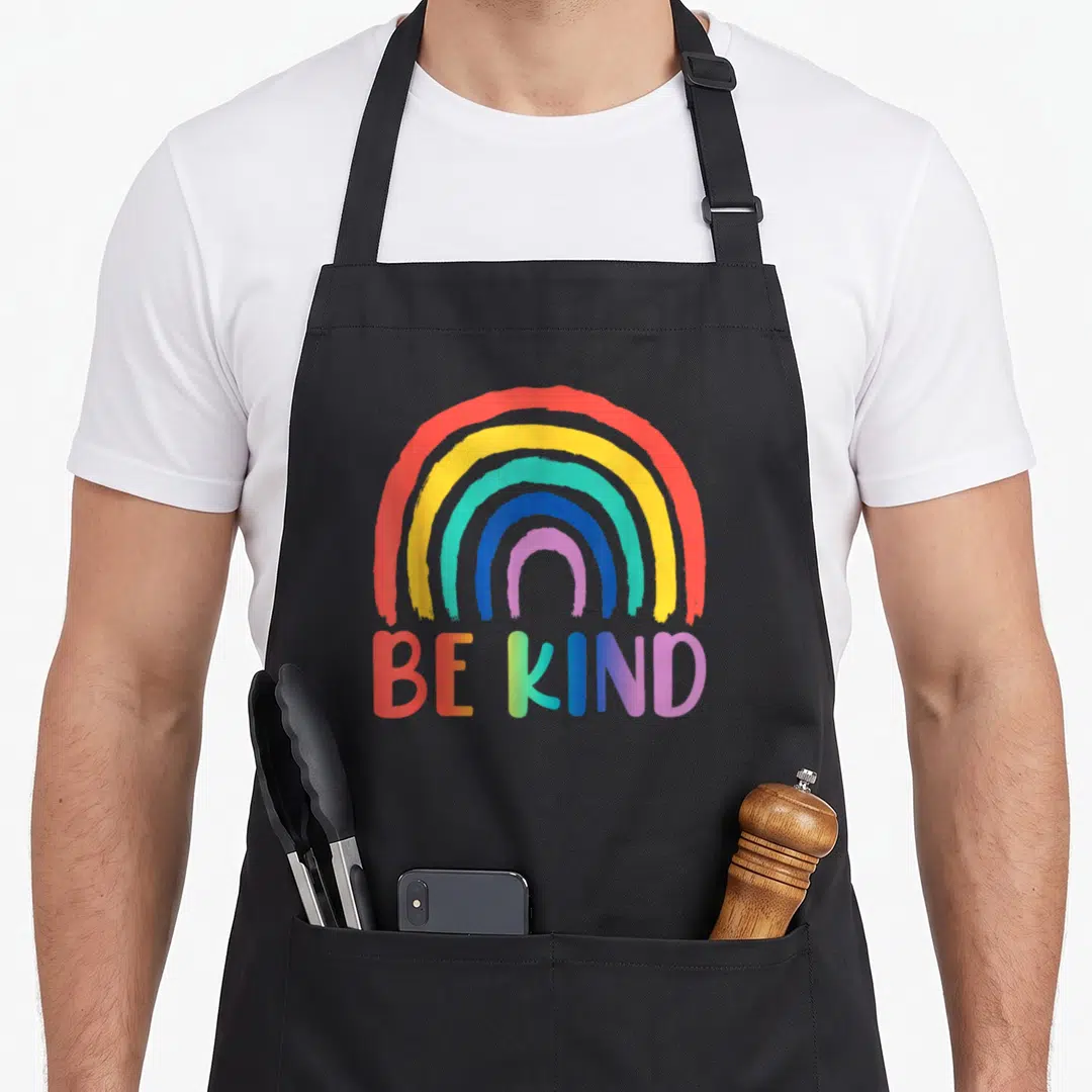 Choose rainbow apron - Rainbow arch and BE KIND gradient text on grey background — shown on a black cotton canvas apron against a white background