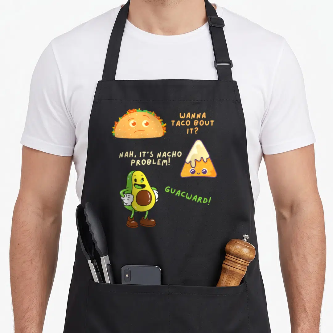 Nacho taco apron - Cartoon taco, cheese-dripping nacho, and standing avocado with punny text in orange yellow green — shown on a black cotton canvas apron against a white background