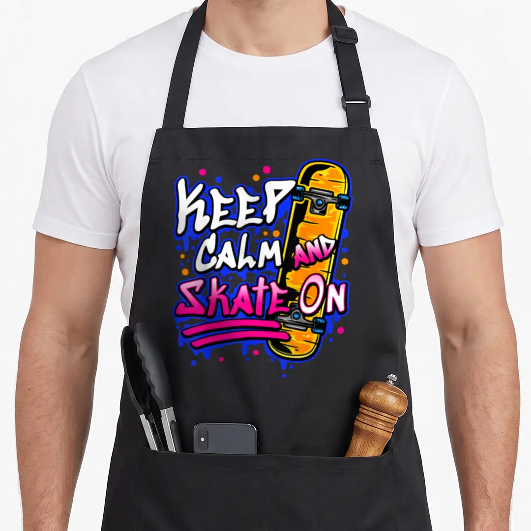 Cute skateboarding skateboard funny apron - Stacked KEEP CALM AND SKATE ON text next to vertical orange skateboard — shown on a black cotton canvas apron against a white background